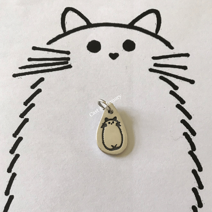 drawing of cat inscribed on silver charm