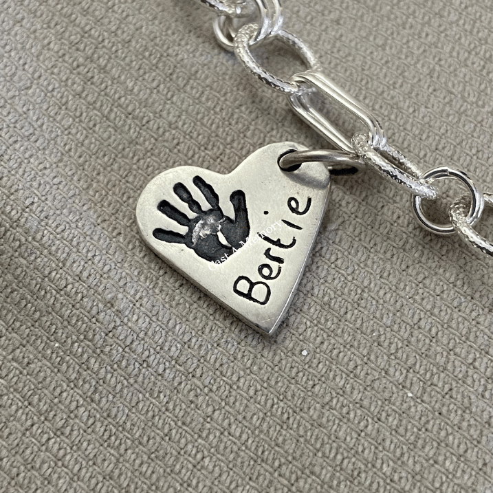 small silver heart charm with hand print impression and name inscribed on chain