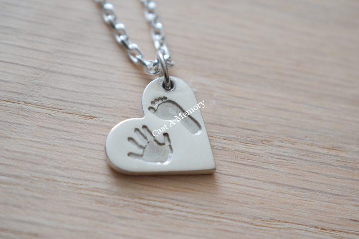 Silver heart shaped pendant necklace with hand and foot print