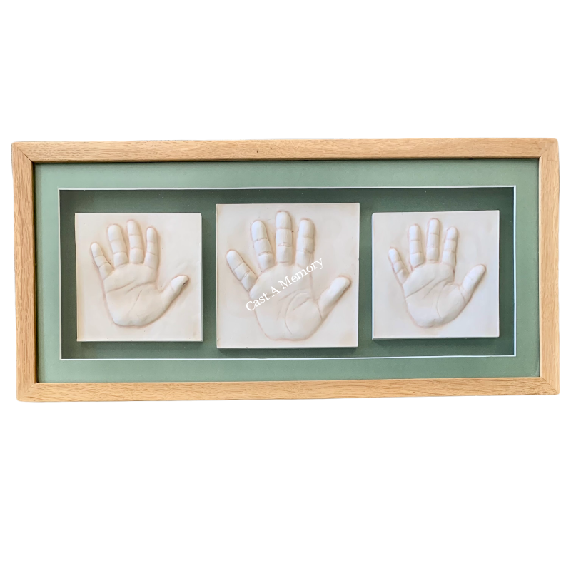 Clay hand impressions of siblings in a light wooden frame