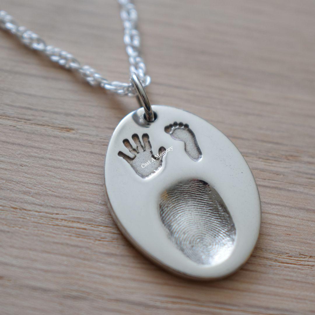 finger print on a silver charm necklace with hand and foot print