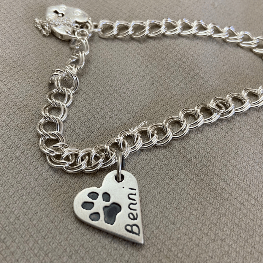 small bracelet with a dog paw print on silver heart shaped charm and engraving of name Benni