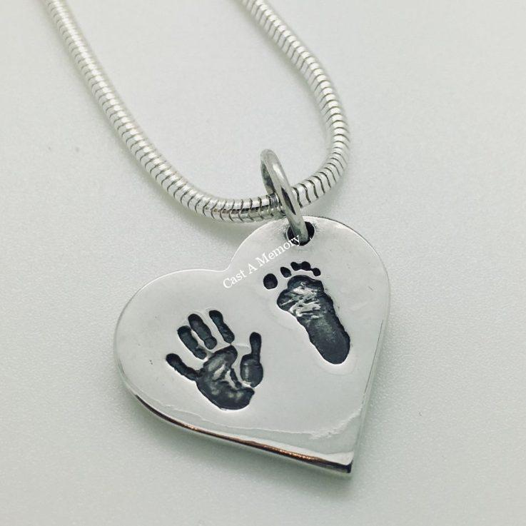 hand and foot print on silver heart shaped charm