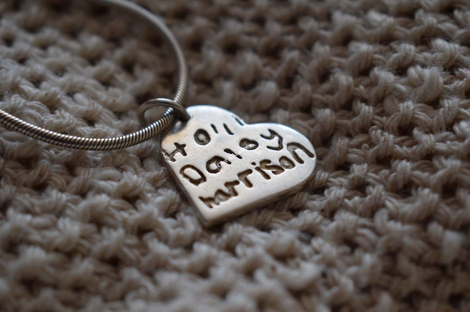 childrens name inscribed on a silver necklace charm