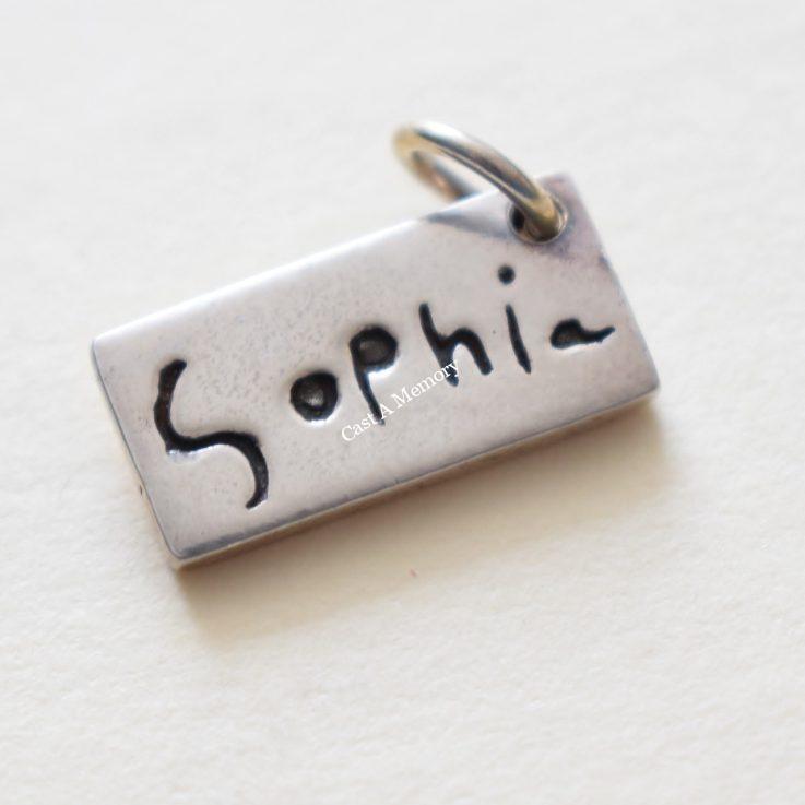 tiny silver charm with childs first name writing